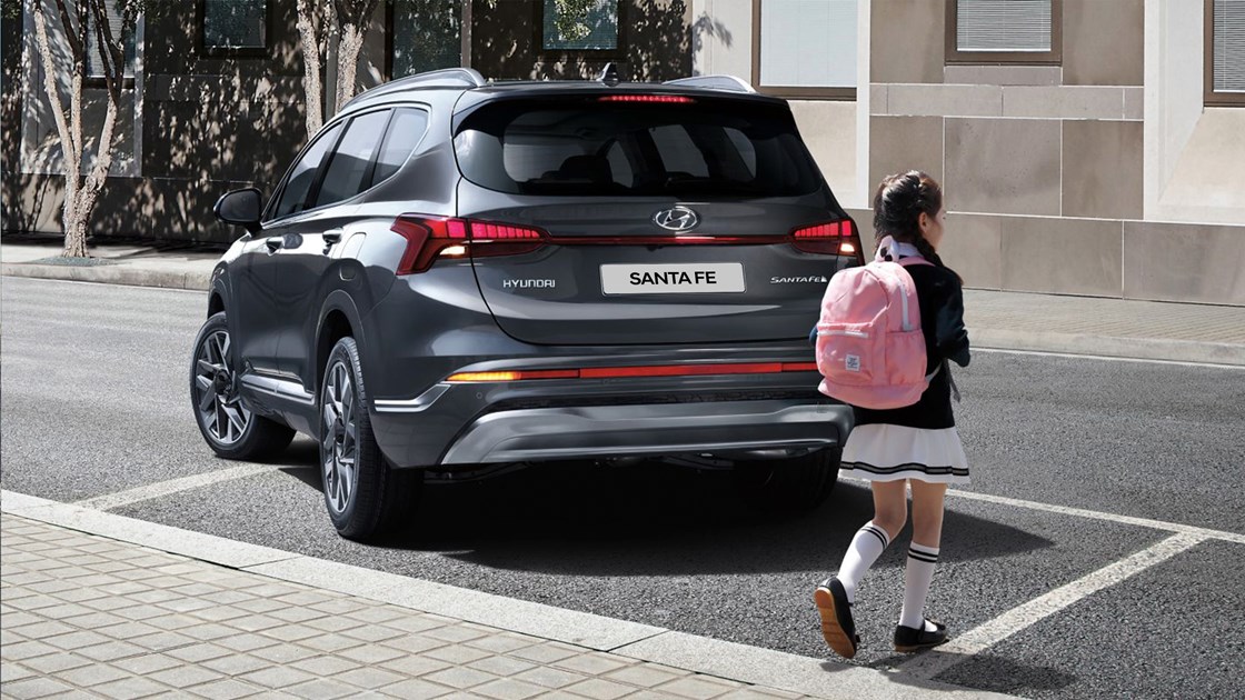 Ett barn passerar baksidan på en mökgrå Hyundai SANTA FE.